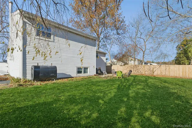 a view of backyard with barbeque grill potted plants and a large tree