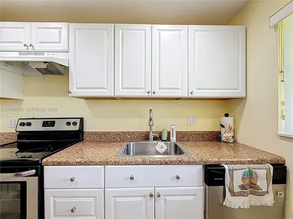 a kitchen with granite countertop a sink a stove and cabinets