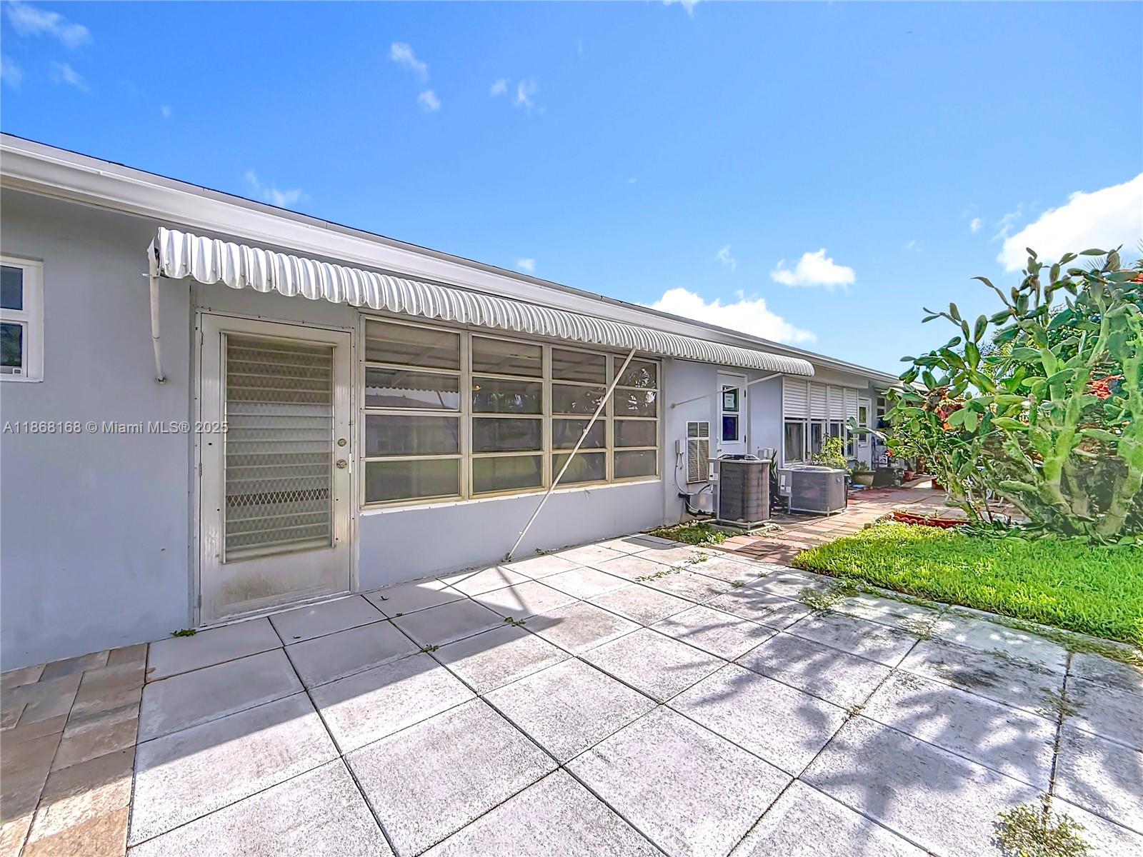 290 Main Boulevard, Unit C Boynton Beach, FL 33435 - Photo 42 of 56 a front view of a house with a large window and a table and chairs in porch