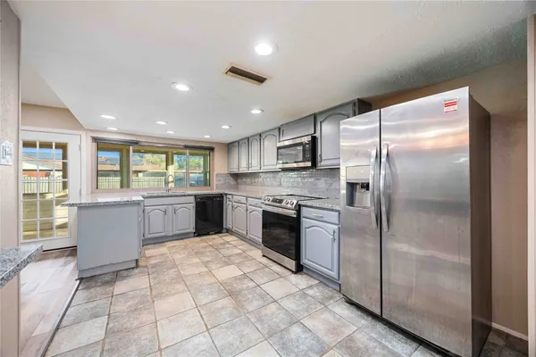 a large kitchen with a refrigerator a counter top space cabinets and stainless steel appliances
