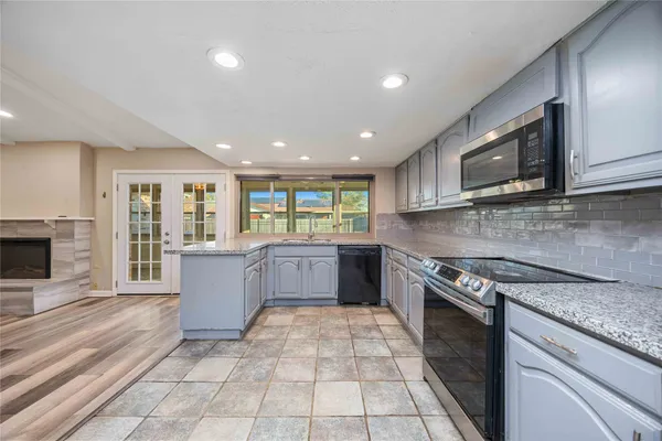 a large kitchen with stainless steel appliances granite countertop a stove top oven a sink dishwasher a dining table and chairs with wooden floor