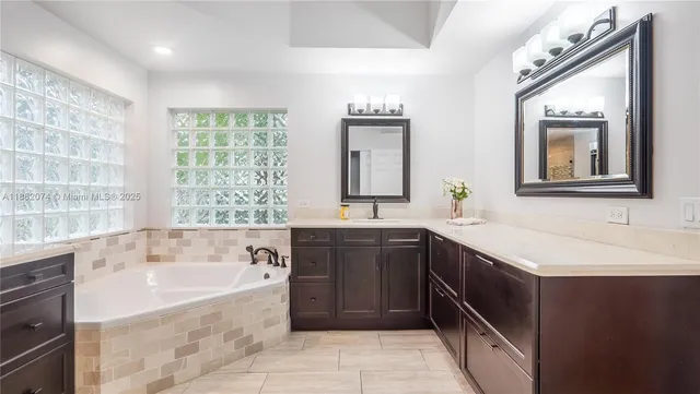 a spacious bathroom with a tub sink and mirror