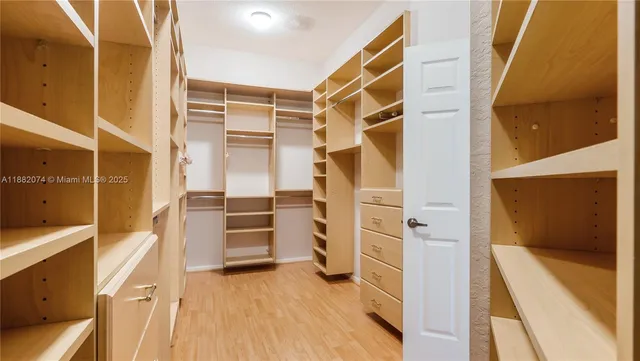 a view of walk in closet with clothes and shoes
