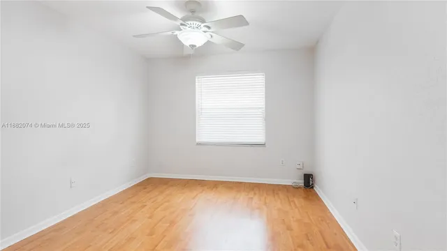 an empty room with a window and ceiling fan