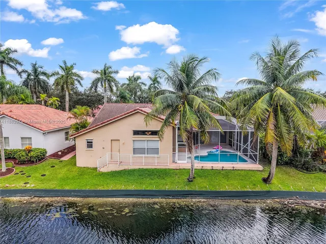 a view of a house with a yard and palm trees