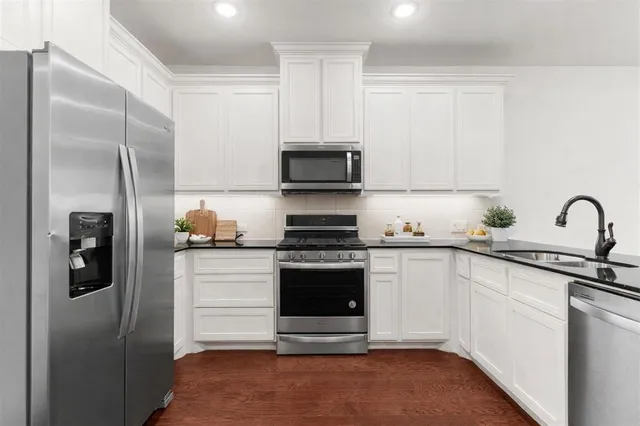 a kitchen with stainless steel appliances granite countertop a stove a refrigerator and a sink