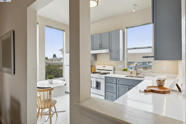 a kitchen with a stove a refrigerator and a view of living room