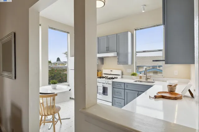 a kitchen with a stove a refrigerator and a view of living room