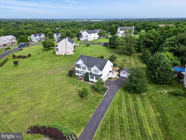 an aerial view of a house with pool big yard and large trees