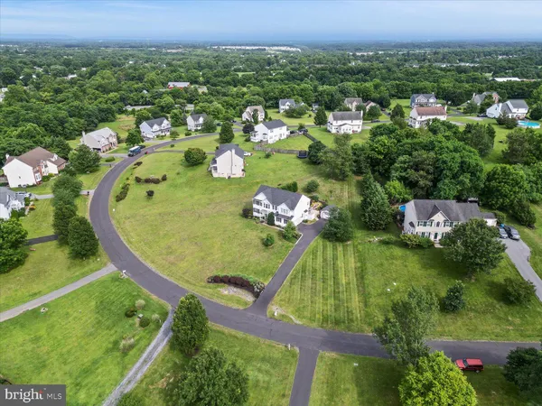an aerial view of a residential houses with outdoor space and trees