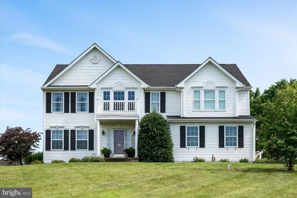 a front view of a house with a yard and trees