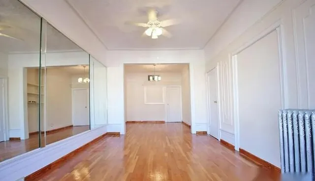 a view of a room with wooden floor and a ceiling fan