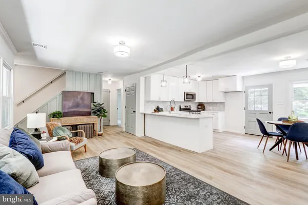 a living room with furniture kitchen view and a wooden floor
