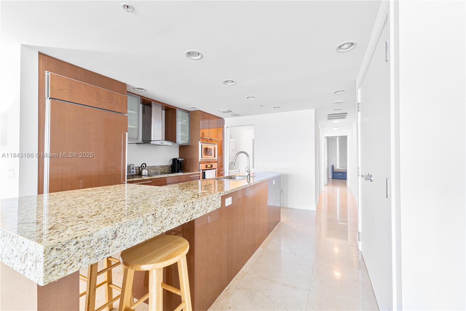 3801 Collins Avenue, Unit 1105 Miami Beach, FL 33140 - Photo 20 of 45 a large white kitchen with kitchen island granite countertop a large counter top and stainless steel appliances