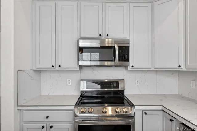 a kitchen with granite countertop white cabinets and stainless steel appliances