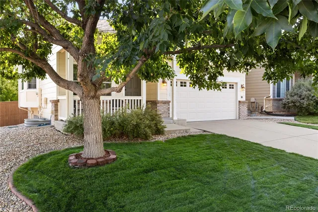 a front view of a house with garden and trees