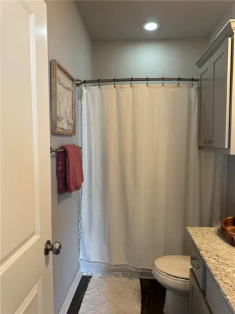a bathroom with a granite countertop toilet and a shower curtain