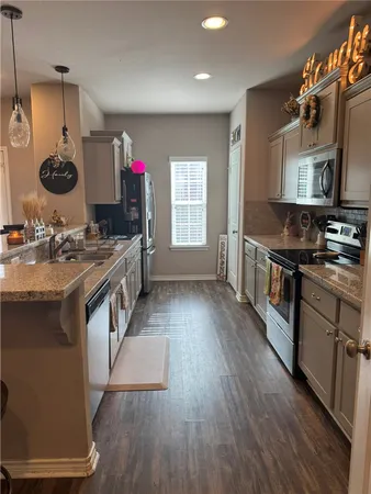 a kitchen with stainless steel appliances granite countertop a stove a sink dishwasher a refrigerator and a dining table with wooden floor