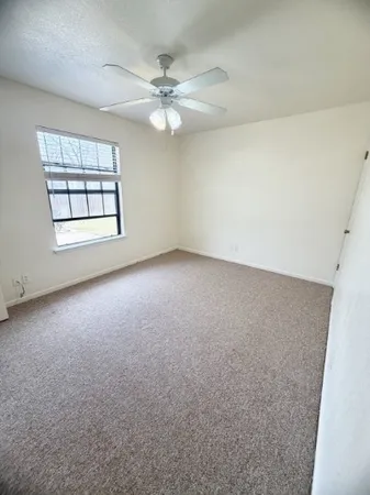 an empty room with windows and chandelier fan