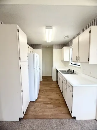 a large white kitchen with a sink and refrigerator