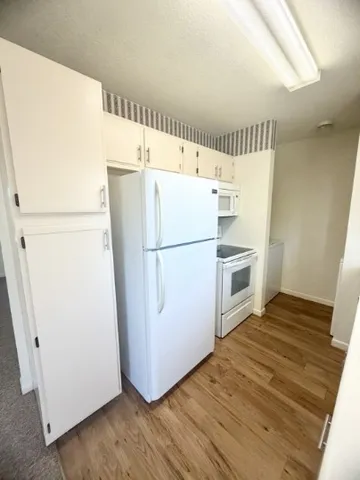 a white refrigerator freezer and a stove sitting inside of a kitchen