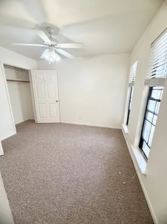 an empty room with windows and fan