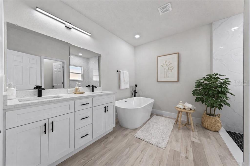 15495 Southwest 49th Avenue Road Ocala, FL 34473 - Photo 41 of 65 a spacious bathroom with a double vanity sink a large mirror a bathtub and a potted plant