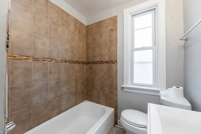 a bathroom with a shower a toilet and a window