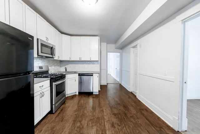 a kitchen with granite countertop a refrigerator a stove top oven a sink and dishwasher with wooden floor