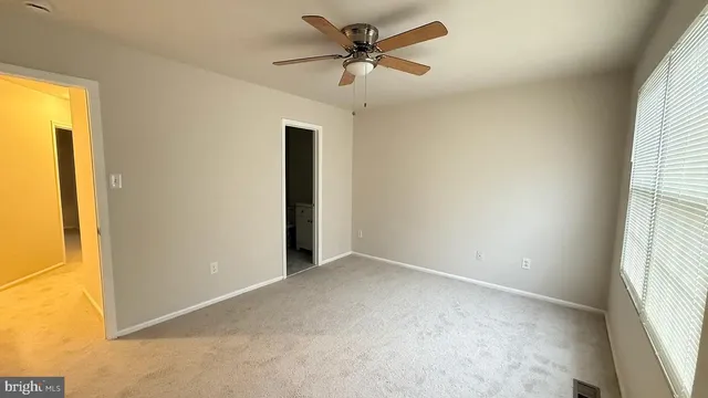 an empty room with a window and a ceiling fan