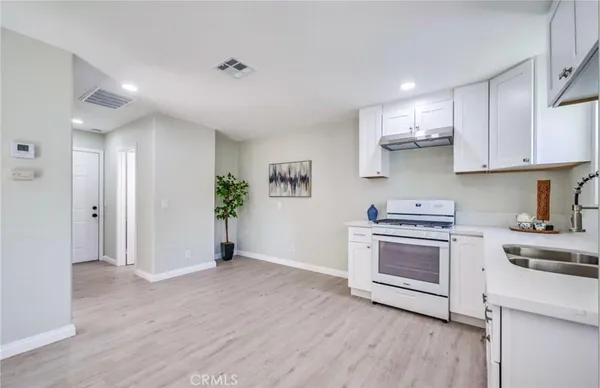 a kitchen with stainless steel appliances white cabinets and wooden floor