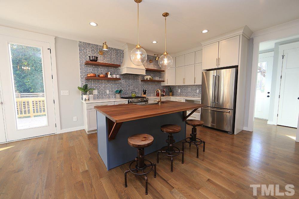 521 Bart Street Raleigh, NC 27610 - Photo 10 of 29 a kitchen with stainless steel appliances granite countertop a stove a refrigerator a sink a dining table and chairs with wooden floor