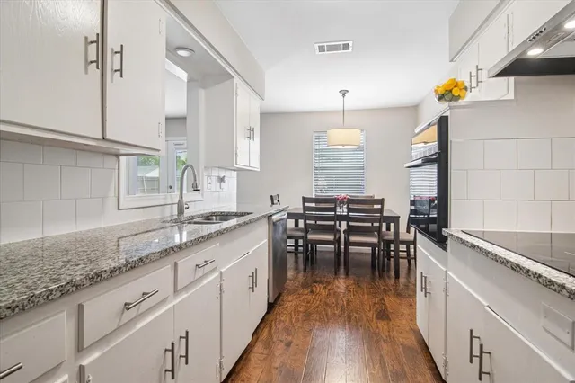 a kitchen with granite countertop a sink appliances and wooden floor