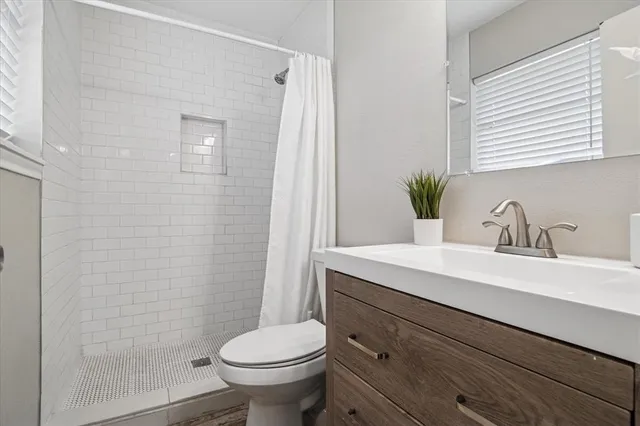 a bathroom with a sink a toilet a mirror and shower