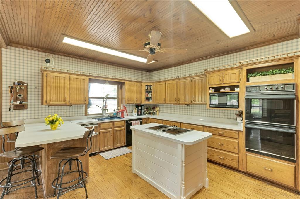 2717 Clear Lake Road Weatherford, TX 76087 - Photo 10 of 40 Kitchen featuring wood-finish flooring, beadboard ceiling, double ovens, and light wood cabinetry