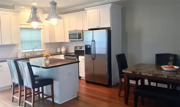 a kitchen with stainless steel appliances granite countertop a dining table chairs refrigerator a sink and dishwasher