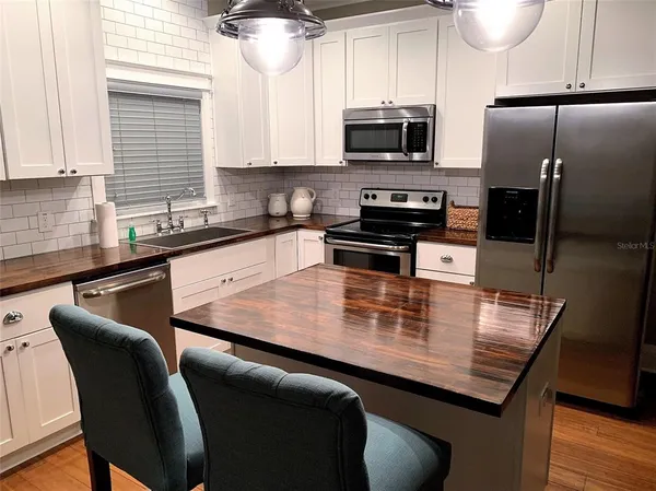 a kitchen with stainless steel appliances a kitchen island wooden cabinets a stove a sink and a refrigerator