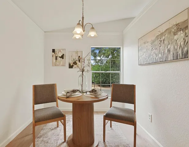 a dining room with wooden floor a chandelier a wooden table and chairs