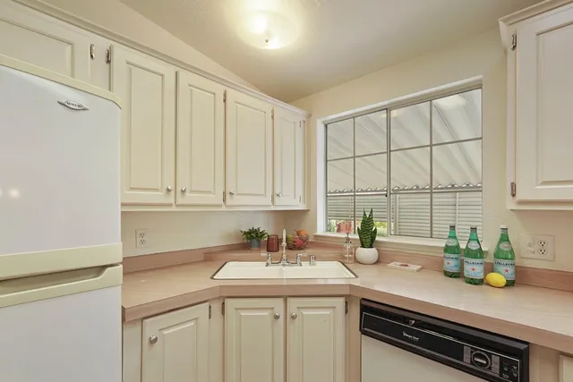 a kitchen with granite countertop a sink cabinets and stainless steel appliances