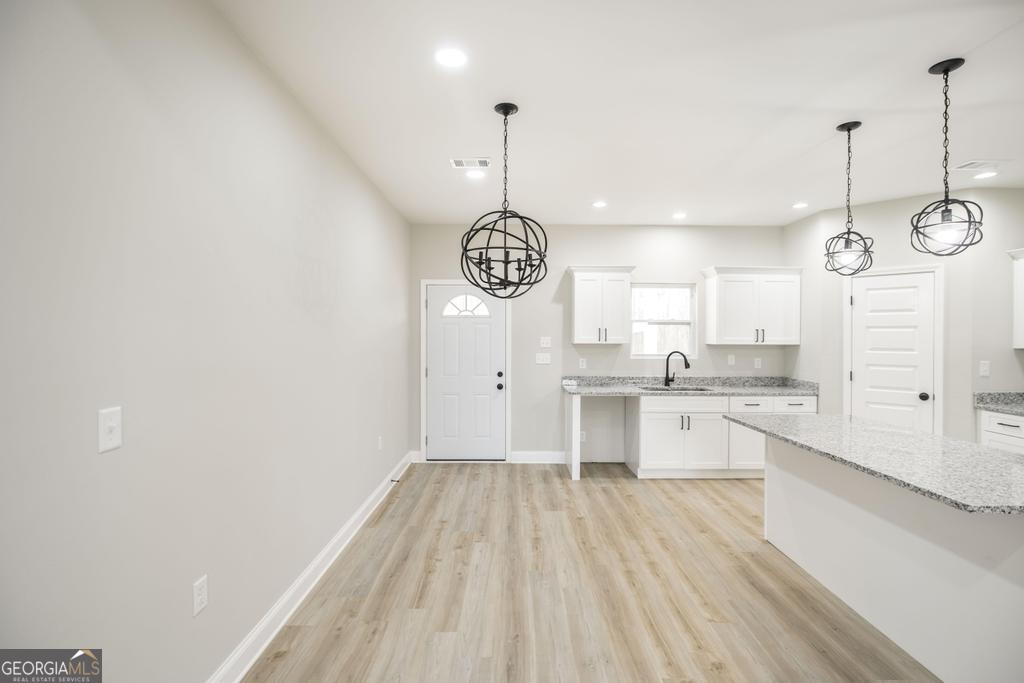 212 Lovett Farm Road East Dublin, GA 31027 - Photo 12 of 26 a kitchen with granite countertop a stove a sink and white cabinets with wooden floor