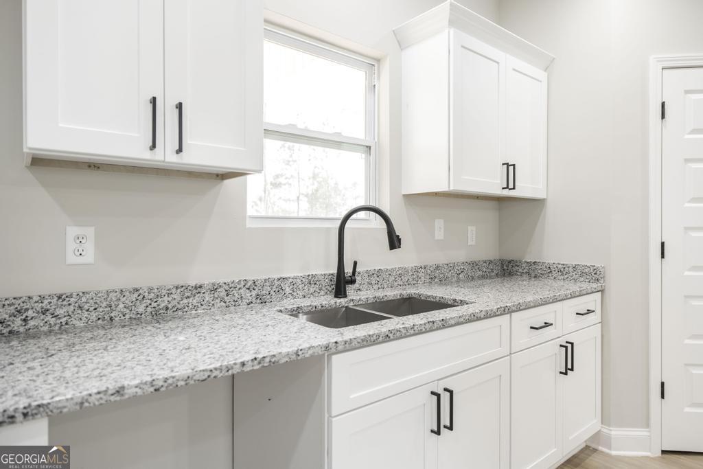 212 Lovett Farm Road East Dublin, GA 31027 - Photo 14 of 26 a sink with granite countertop white cabinets and a window