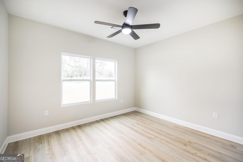 212 Lovett Farm Road East Dublin, GA 31027 - Photo 20 of 26 an empty room with wooden floor ceiling fan and windows