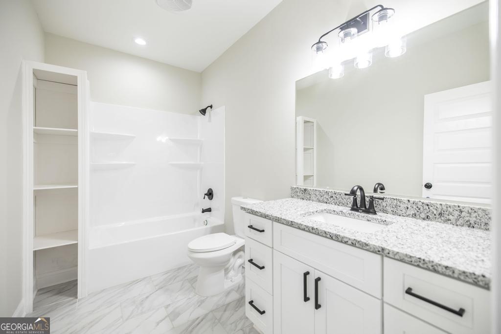 212 Lovett Farm Road East Dublin, GA 31027 - Photo 24 of 26 a bathroom with a granite countertop sink a toilet and bathtub
