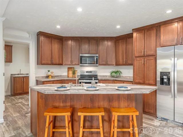 a kitchen with stainless steel appliances granite countertop a stove a sink a microwave a refrigerator and cabinets