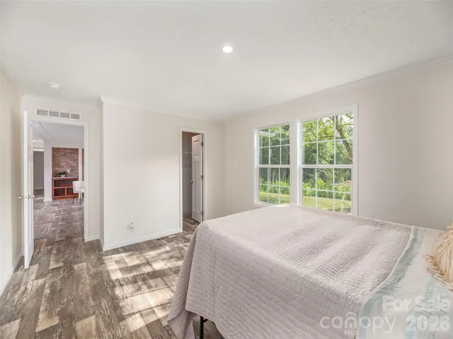 a view of a bedroom with a bed and wooden floor