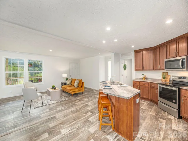 a kitchen with stainless steel appliances granite countertop a stove a sink a refrigerator and a dining table with wooden floor