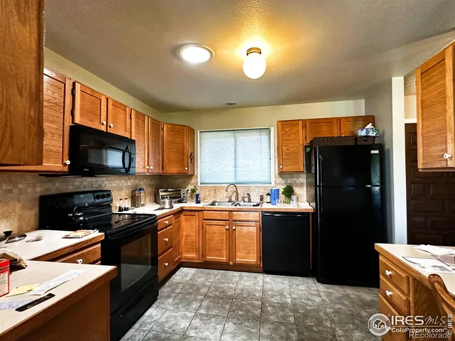 a kitchen with stainless steel appliances granite countertop a refrigerator a sink a stove and black cabinets