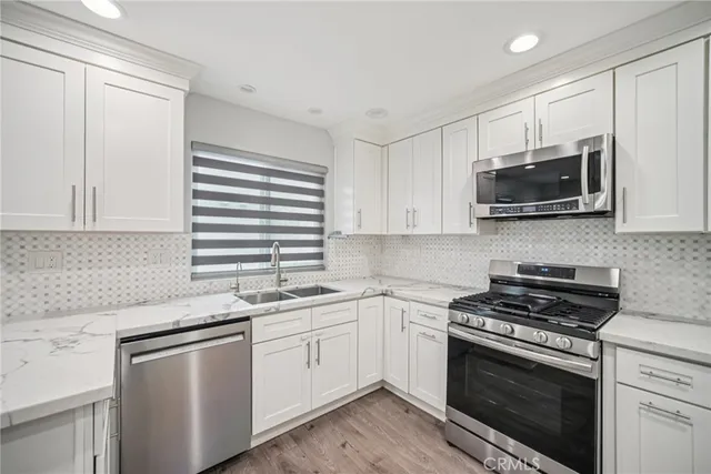 a kitchen with stainless steel appliances granite countertop white cabinets a sink and a stove