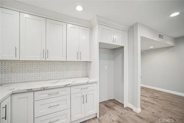 a kitchen with granite countertop white cabinets and a wooden floor