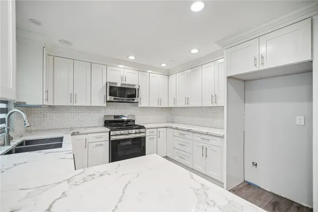 a kitchen with granite countertop white cabinets and stainless steel appliances